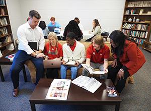 Group of communication students working together on couch in library.